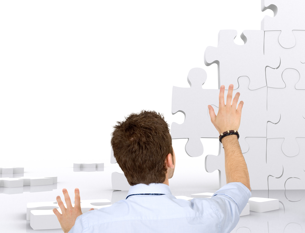 Business man building a puzzle isolated over white