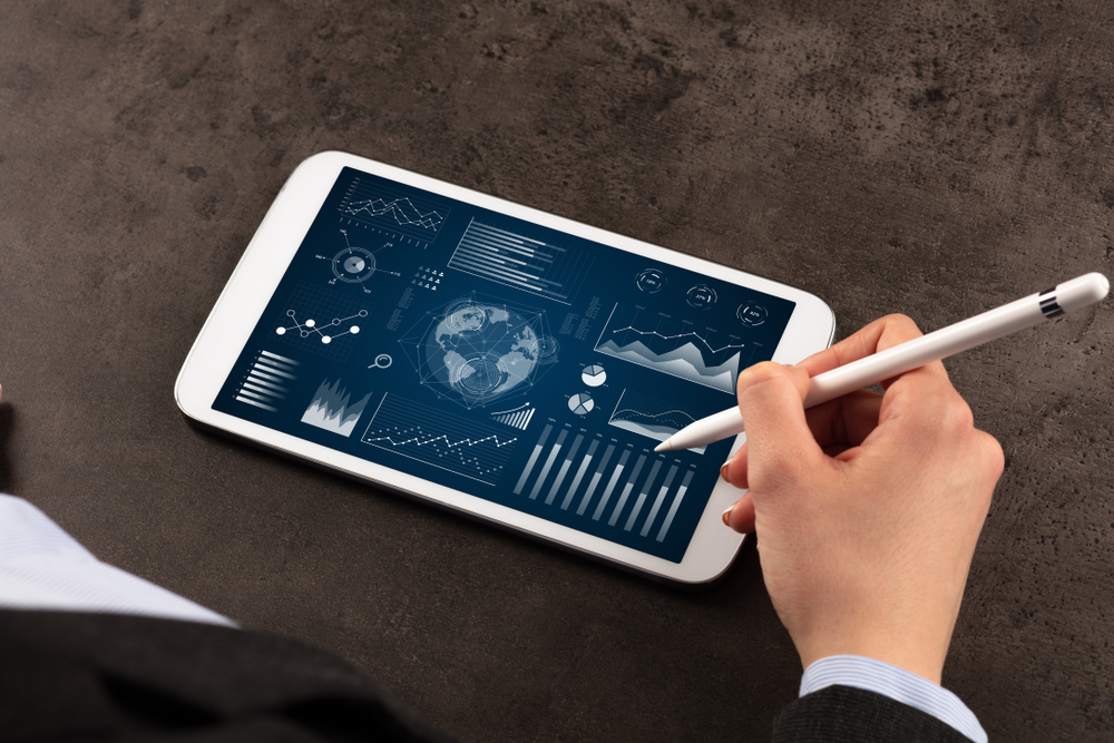 Business woman verifying reports on tablet with pencil in business suit