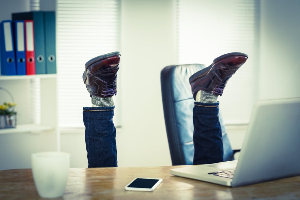 Businessman upside down at his desk in his office