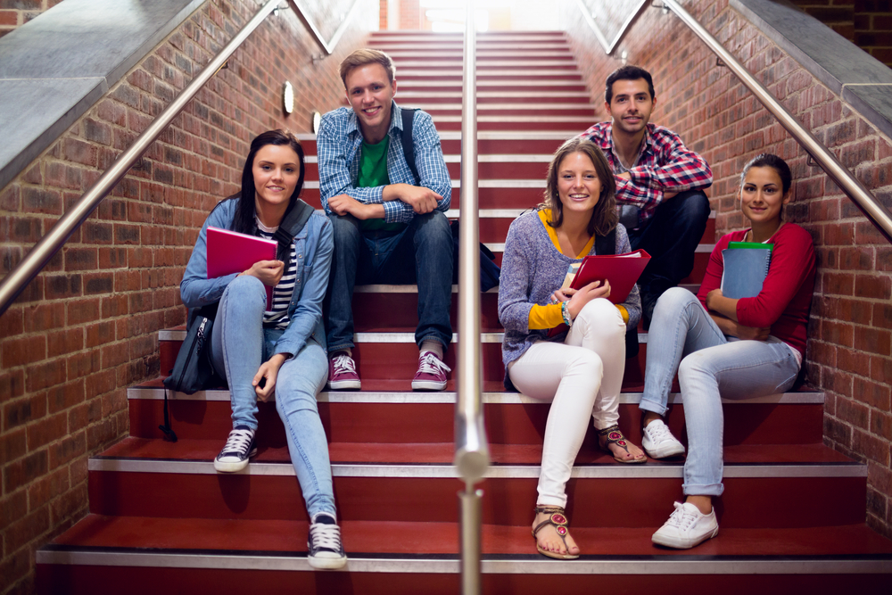Group portrait of young college students sitting on stairs in the college