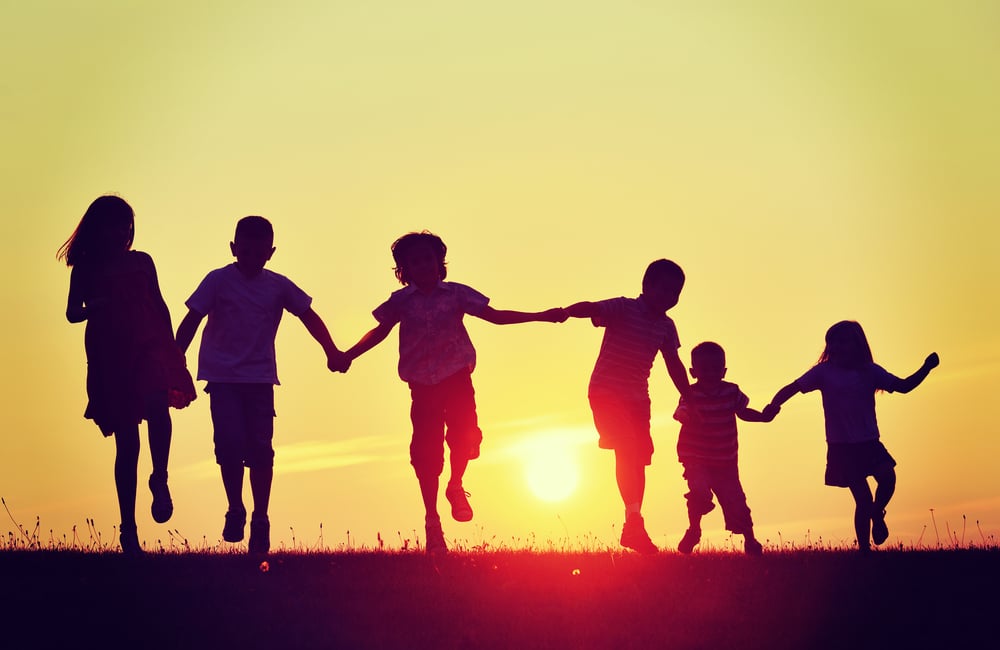 Happy children silhouettes on summer meadow running and jumping