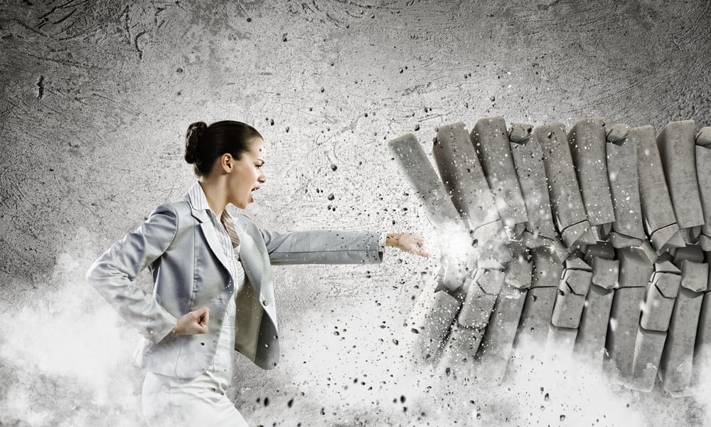 Image of businesswoman breaking bricks with hand