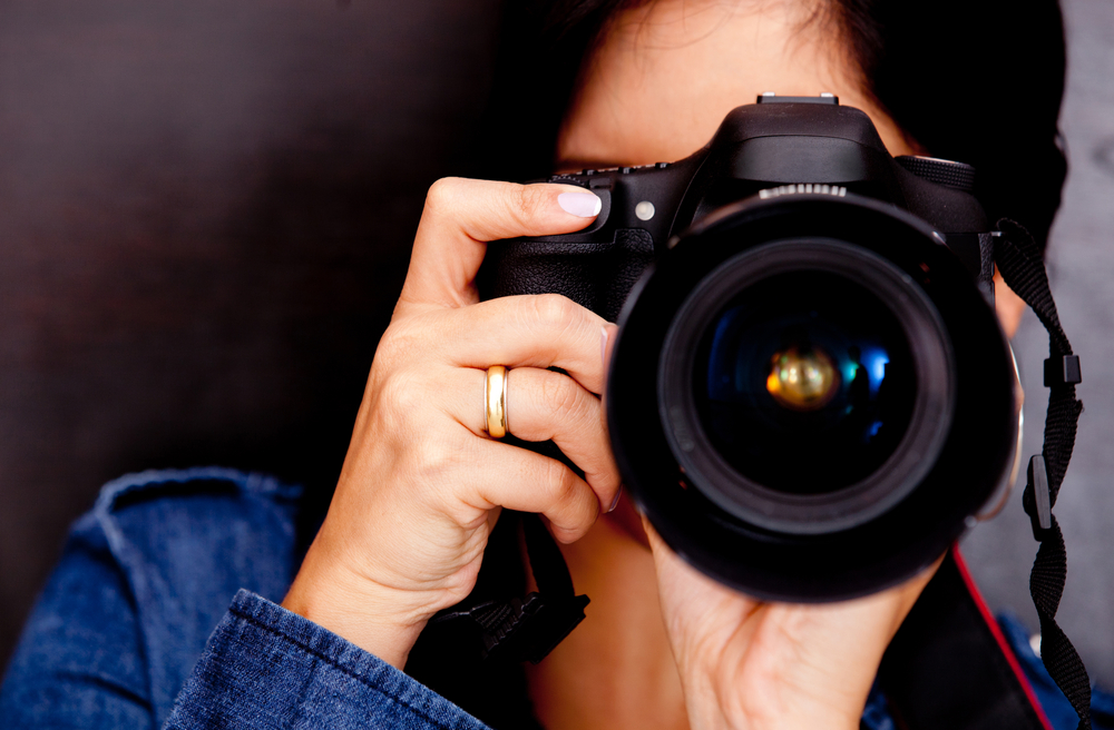 Portrait of a photographer covering her face with the camera